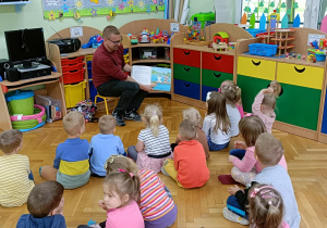 Pan Piotr pokazuje dzieciom obrazek znajdujący się w książce.